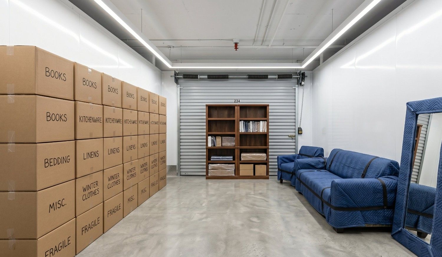 Organized self storage unit interior showing furniture and boxes neatly stacked